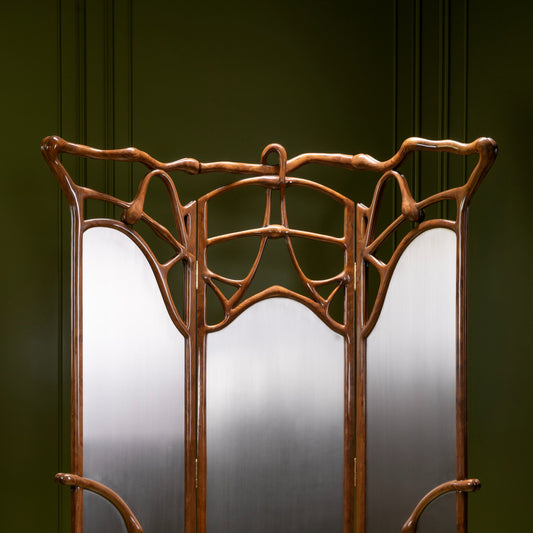 An Art Deco style three-panel folding screen with a polished dark brown curved metal frame and frosted glass panels, set against a dark green paneled wall.